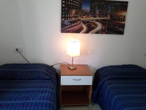 Pokój z 2 łóżkami i lampką na stoliku nocnym w obiekcie Appartamento Elegante E Panoramico Con Splendida Vista Mare w mieście Buggerru
