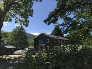 a black house with cars parked in front of it at Glencoe Youth Hostel in Ballachulish