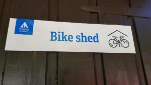 un letrero de cobertizo para bicicletas colgando de una valla de madera en Glencoe Youth Hostel en Ballachulish