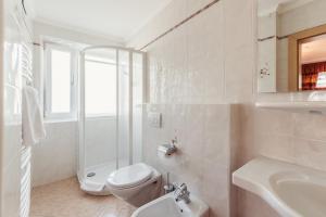 a white bathroom with a toilet and a sink at Pension Wiesenrain in Maranza