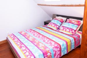 een slaapkamer met een bed met kleurrijke lakens en kussens bij Maison de village Salency in Salency