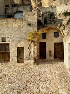 a stone building with doors and a tree in it at Sextantio Le Grotte Della Civita in Matera