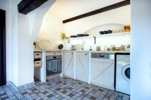 Una cocina con gabinetes blancos y lavadora y secadora. en Hét Fenyő Vendégház / Seven Pines Holiday House, en Sukoró