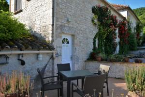 un patio avec des chaises et une table en face d'un bâtiment dans l'établissement La Bordette, à Valeilles