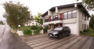 a black car parked in front of a house at Manahlid Apartment in Akureyri