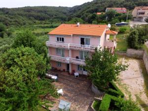 a large pink house with an orange roof at Apartmani Margeta in Rab