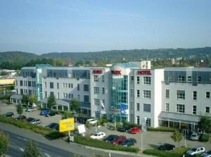 ein großes Gebäude mit Autos auf einem Parkplatz in der Unterkunft Euro Park Hotel Hennef in Hennef