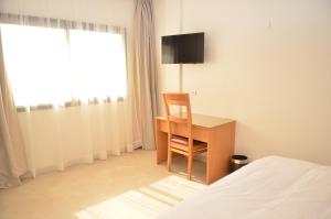 a bedroom with a desk and a chair next to a bed at Hotel El Bachir in Dakhla