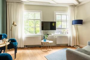 a living room with a tv and two windows at Canal Wow Suites Amsterdam in Amsterdam