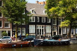 a couple of boats parked in the water in front of buildings at Canal Wow Suites Amsterdam in Amsterdam