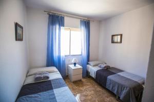 two beds in a room with blue curtains and a window at Las Gondolas Seaview in La Manga del Mar Menor