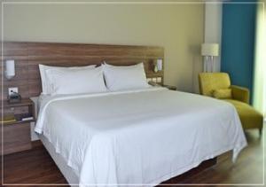 a bedroom with a large white bed and a yellow chair at Holiday Inn Express Villahermosa by IHG in Villahermosa