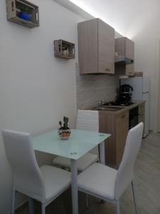 een keuken met een witte tafel en witte stoelen bij U dammusu ra cianta in Modica