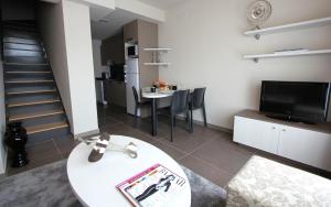 a living room with a white table and a kitchen at Pierre & Vacances Barcelona Sants in Barcelona