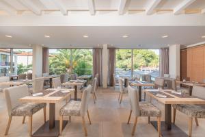 ネオス・マルマラスにあるPoseidon Hotel Sea Resortのテーブルと椅子、大きな窓のあるレストラン