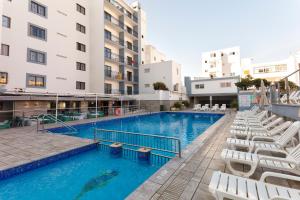 a swimming pool with white chairs and a hotel at Hotel Brisa Ibiza - Adults only in San Antonio