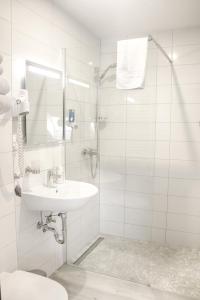 a white bathroom with a sink and a shower at Hotel zur Eiche in Salzkotten