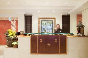 a woman is standing behind a reception desk at Kipling Manotel in Geneva