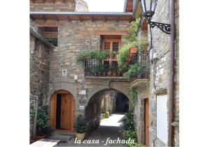 an alley in an old stone building with a door and flowers at Casa Dueso in El Pueyo de Araguás