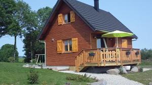 a log cabin with a deck and an umbrella at Chalet des Clarines in Saint-Genès-Champespe