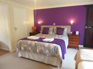 カーマーゼンにあるNeuadd Wen Guest Houseの紫の壁の大型ベッド付きの紫のベッドルーム1室