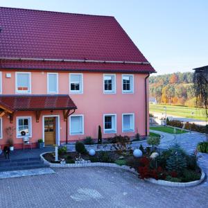 ein rosa Haus mit rotem Dach in der Unterkunft Stixenhof - Ferienwohnung Heidi Nehmeier in Haundorf