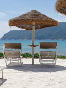 two chairs under a straw umbrella on the beach at Appartamento TERESA in Rio nellʼElba