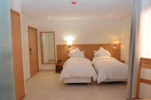 a bedroom with two beds with white sheets and a mirror at Hotel El Bachir in Dakhla +19 photos