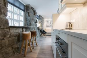a kitchen with wooden stools and a stone wall at GreenKey Apartment SK2 in Reykjavík