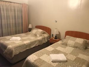 1 dormitorio con 2 camas y ventana en Hospedaje Baquedano, en Puerto Natales