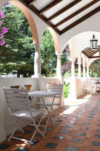 a white table and chairs on a patio with trees at Quinta da Fogueira in Anadia