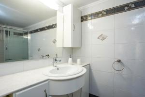a white bathroom with a sink and a mirror at Flora's Place in Rhodes Town
