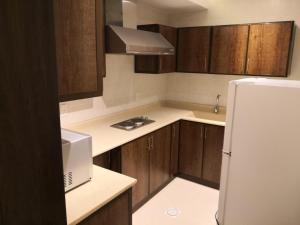 a kitchen with wooden cabinets and a white refrigerator at MJ Apartments in Al Khobar +24 photos