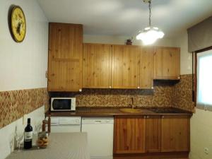una cucina con armadi in legno, lavandino e forno a microonde di Casa Galilea a Galilea