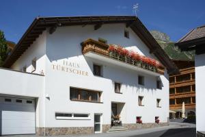 ein weißes Gebäude mit Blumen auf dem Balkon in der Unterkunft Frühstückspension Türtscher in Galtür