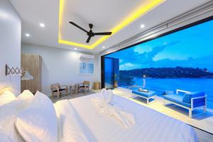 - une chambre avec un lit et une grande fenêtre avec vue dans l'établissement Samui Bayside Luxury Villas, à Choeng Mon Beach
