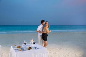 a man and woman standing next to a table on the beach at Golden Parnassus Resort & Spa - All Inclusive (Adults Only) in Cancún