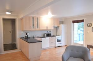 uma cozinha com armários brancos e uma cadeira em Apartment 2, Herand, Hardanger em Herand