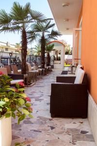 un patio avec des chaises et des palmiers sur un bâtiment dans l'établissement Hotel Cristall, à San Benedetto del Tronto