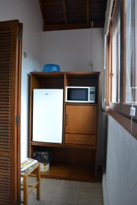 a kitchen with a microwave and a refrigerator at Ex Pousada Vale do Bosque - Aluguel por temporada in Gramado
