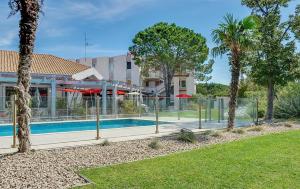 une piscine avec des arbres et un bâtiment dans l'établissement ibis Salon de Provence, à Salon-de-Provence