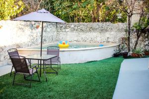 uma mesa com cadeiras e um guarda-sol ao lado de uma piscina em Santiago Magic house em Mérida