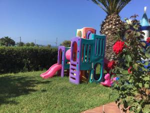 a toy playground in the grass next to a tree at Hotel Oasis in Kyparissia