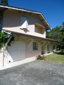 une maison blanche avec un garage et une allée dans l'établissement A la Cerisaie, à Carignan