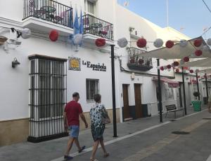 a man and a woman walking down a street at Hostal Boutique La Española by Bossh Hotels in Rota