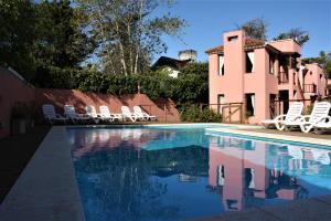 a swimming pool with chairs and a house at LA AGUADA - Villa de Mar in Villa Gesell