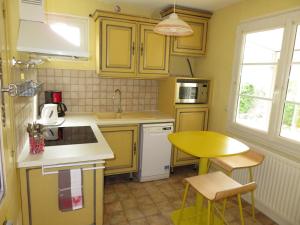 アンボワーズにあるGîte La Pierre Qui Tourneのキッチン(黄色のキャビネット、テーブル、シンク付)