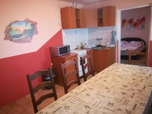 una cocina con mesa y una pequeña cocina con una habitación en Tiszavirág Apartmanház, en Szeged