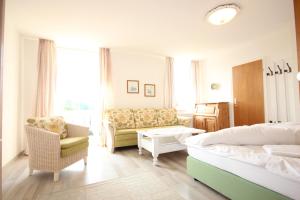 a bedroom with a bed and a couch and a chair at Hotel Villa Sisi in Pöcking