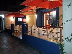 un restaurant avec des parasols rouges, des tables et des chaises dans l'établissement London House, à Bizerte